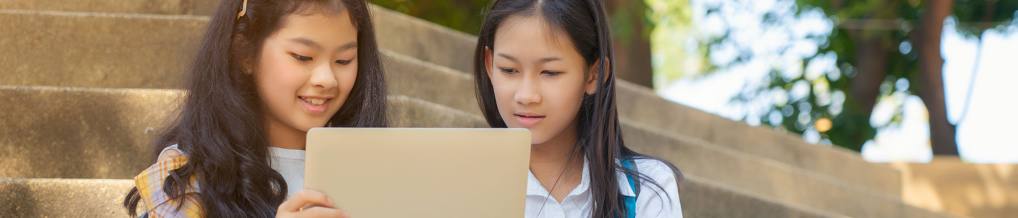 Two girls on a laptop outside