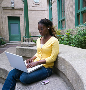 High school student sitting outside on her laptop