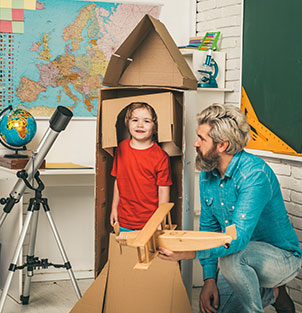 Teacher building a cardboard rocket for young boy
